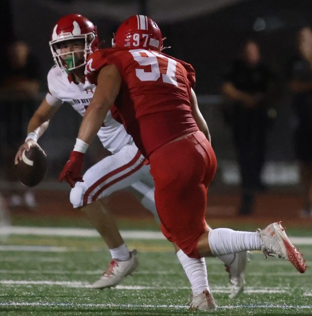 Naperville Central defensive lineman Jason Figg (97) attempts to sack Hinsdale Central quarterback Riley Contreras (1) at Memorial Stadium in Naperville on Friday, Aug. 30, 2024. (Talia Sprague/for the Naperville Sun)