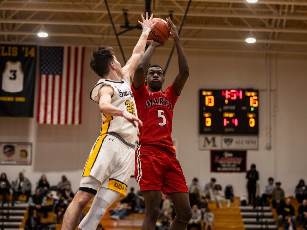 Marist's Stephen Brown (5) takes a jump shot as Marian Catholic's Zack Sharkey (22) defends during an East Suburban Catholic game in Chicago Heights on Friday, Jan. 26, 2024.