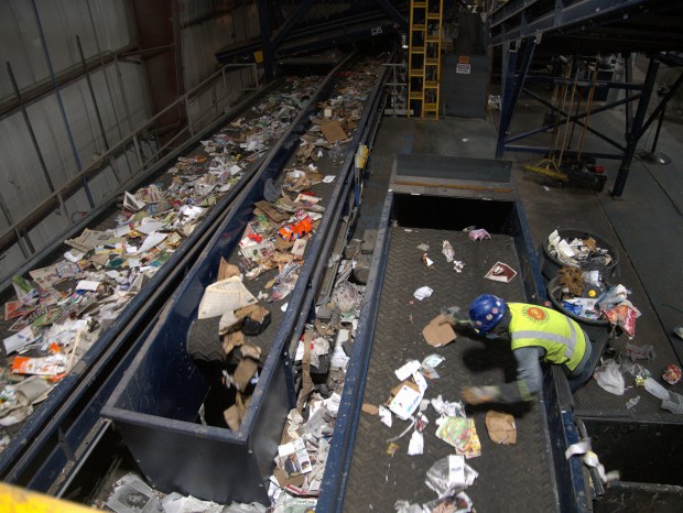 A worker at the Northbrook Recycling Facility keeps watch over a conveyor belt of material.