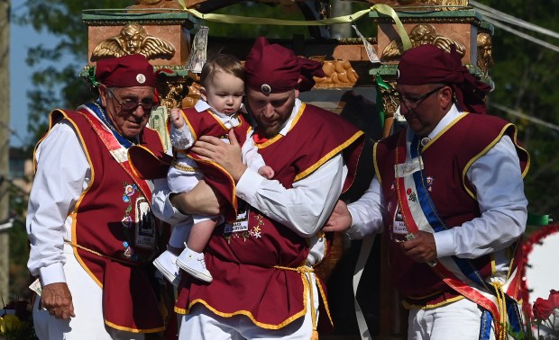 Far left, on the shrine, is Sam Bondi of Hoffman Estates, during the time with people of all ages are brought to the sacred image at the beginning of the procession of the shrine at the annual Religious Feast of Maria SS Lauretana of Altavilla Milicia in Niles on Sept. 1, 2024. (Karie Angell Luc/Pioneer Press)