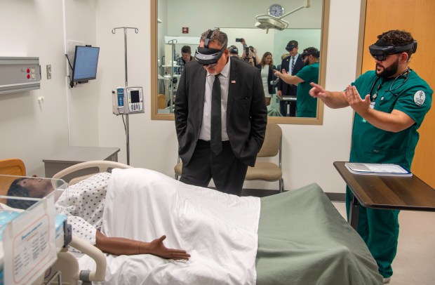 U.S. Secretary of Education Miguel Cardona, center, is shown augmented-reality training materials by nursing student Aaron O'Reilly at the Valparaiso Ivy Tech Community College campus on Wednesday, Sept. 4, 2024. (Michael Gard/for the Post-Tribune)