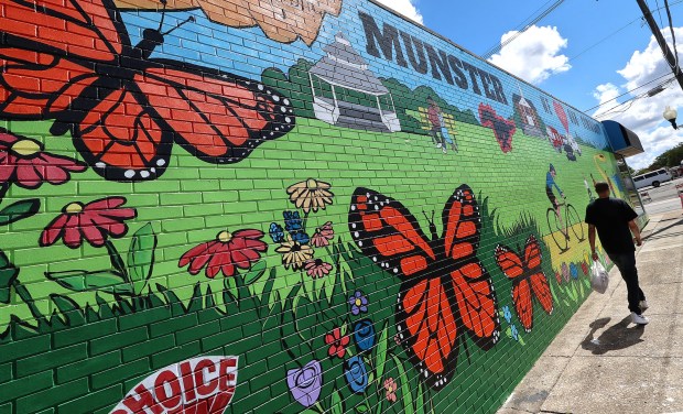 A walking man is dwarfed by a new mural on the northeast corner of Ridge Rd. and Meadow Ave. in Munster. The Munster Police Department Choice Community Council created its first anticrime/beautification mural and organizers hope it is the first of many. The ceremony took place on Saturday, Sept. 7, 2024. (John Smierciak/Post Tribune)