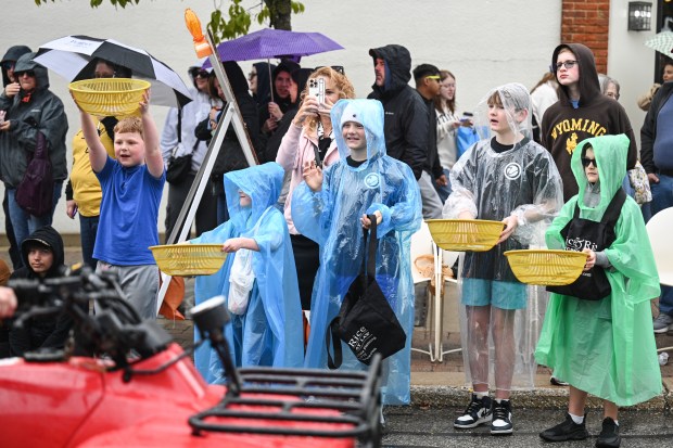 Children in ponchos hold out their bowls for candy during the Valparaiso Popcorn Festival Parade on Saturday, Sept. 7, 2024. (Kyle Telechan/for the Post-Tribune)