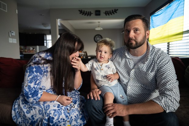 Crown Point resident Elmira Miocic, on left, with husband Antony, kisses her son Alan's hand as she speaks about her journey to the US and previous efforts to bring her family over from Ukraine, in her Crown Point home on Wednesday, Sept. 11, 2024. (Kyle Telechan/for the Post-Tribune)