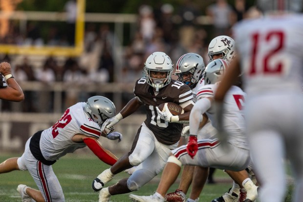 Mount Carmel's Danyil Taylor (10) slips past a pair of defenders from the Hun School of Princeton from New Jersey after a reception during a nonconference game in Chicago, on Thursday, Aug. 29, 2024. (Vincent D. Johnson/for the Daily Southtown)