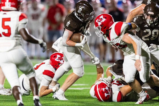 Joliet Catholic's Larry Stringham tries to move forward while Marist's Michael Flynn grabs his ankle and Joshua Loera holds onto his shirt during a CCL/ESCC Green game in Joliet on Friday, Sept. 20, 2024. (Vincent D. Johnson / Daily Southtown)