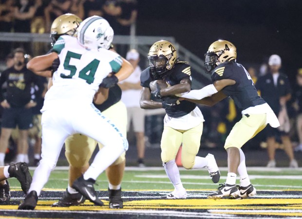 Richards quarterback Noah Escobedo (7) hands the ball off to Richards running back Ladarius Foster (21) during a South Suburban Red Conference football game at Richards High School in Oak Lawn on Friday, Sept. 20, 2024. (Talia Sprague / Daily Southtown)