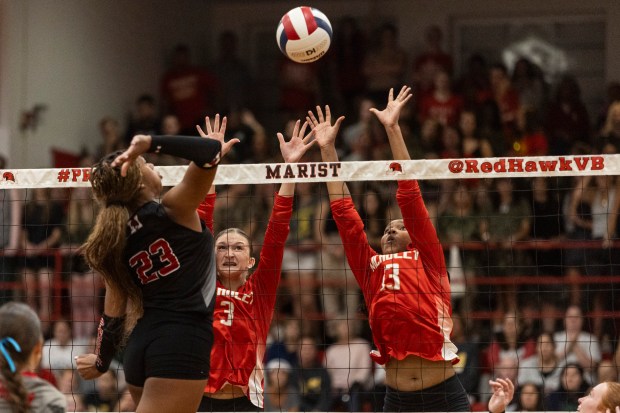 Mother McAuley's Cayla Prohaska (3) and Mother McAuley's Sydney Buchanan (13) attempt to block a hit by Marist's Cassidy Cage (23) during a nonconference game in Chicago on Thursday, Sept. 26, 2024. (Vincent D. Johnson / Daily Southtown)