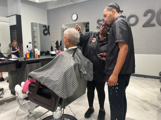 Barbering instructor Ayana Goodwin shows student Ivan Walker how to cut his client's hair Sept. 4, 2024 at Thornridge High School's Studio 205. (Olivia Stevens/Daily Southtown)