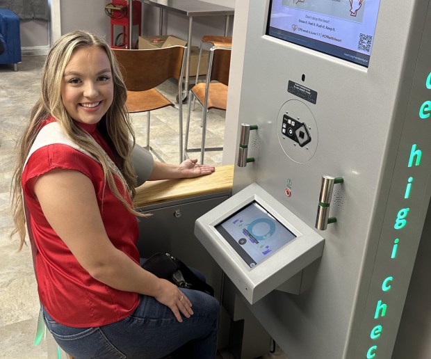 Pageant winner Rhiannon Graham uses the new blood pressure kiosk during a ceremony Aug. 31 at Free N Deed Market in Dolton. Graham, Miss Capital City, has focused on advocacy for single parent households for her service initiative. (American Heart Association)