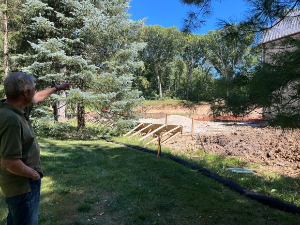 New Lenox Township resident Bob Heniff points Sept. 3, 2024, to the backyard of his neighbor's house where a pool house roughly the same size of his house is proposed. He is concerned with erosion in the neighbor's backyard as well as a septic system that is near his property line. (Michelle Mullins/for the Daily Southtown)