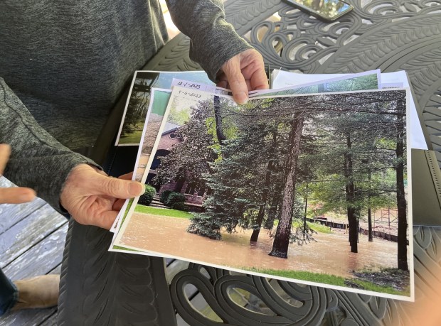 New Lenox Township resident Jean Heniff shows photos Sept. 3, 2024, of their front yard underwater when they say construction of a luxury house next door altered the lay of the land. (Michelle Mullins/for the Daily Southtown)