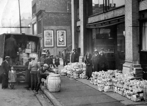 Outside the original Chicago Defender building, newspaper founder Robert Sengstacke Abbott stands amidst bundles of donations to be given out as charitable gifts in Chicago, circa.1910s. The Chicago Defender encouraged those in the south to travel north to Chicago during the Great Migration. (Robert Abbott Sengstacke Collection/Getty Images)