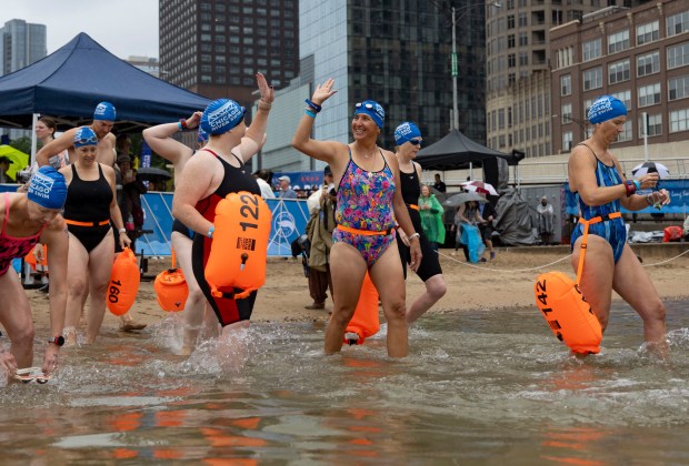 Heather Berken, center, of Wisconsin and other swimmers wade into the water off Ohio Street Beach to begin the race on Sunday, Sept. 22, 2024. (Brian Cassella/Chicago Tribune)