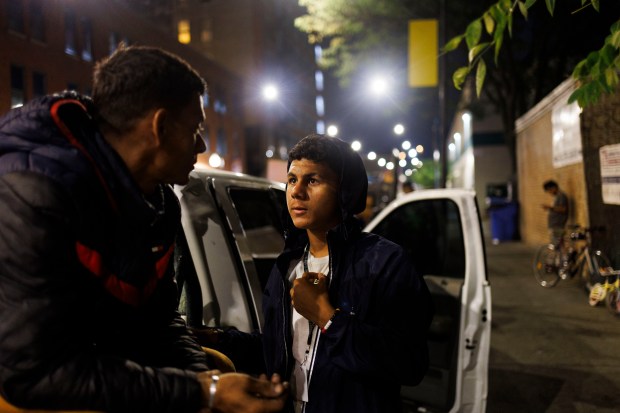 Reynaldo Perdoma, 14, right, talks with his father Yohan Perdomo, 37, outside a migrant shelter on the Lower West Side on Monday Sept. 9, 2024, in Chicago. Reynaldo and his father Yohan have been sleeping in the truck outside the shelter while Reynaldo attends school nearby. Recently the city announced it would be closing the shelter on Oct. 1st. (Armando L. Sanchez/Chicago Tribune)