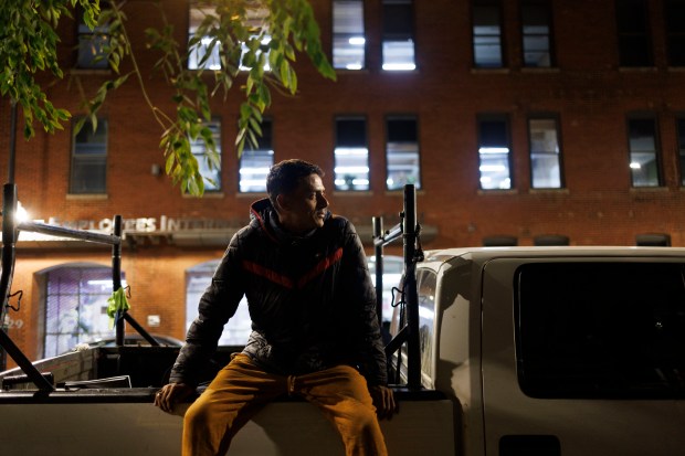 Yohan Perdomo, 37, sits on a truck outside a migrant shelter on the Lower West Side on Monday, Sept. 9, 2024, in Chicago. Yohan and his son Reynaldo Perdoma, 14, have been sleeping in the truck outside the shelter while Reynaldo attends school nearby. (Armando L. Sanchez/Chicago Tribune)