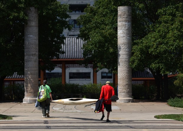 Annette Prince, left, and Jim Tibensky carry a kayak in Chinatown's Ping Tom Park that they used to capture two Pekin ducks in the Chicago River on Sept. 5, 2024. (Stacey Wescott/Chicago Tribune)