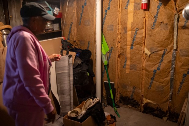 Edie Jacobs takes a look at remaining water damage to the insulation from last summer's flooding in her basement on Tuesday, Sept. 24, 2024, in the Austin neighborhood. (Brian Cassella/Chicago Tribune)