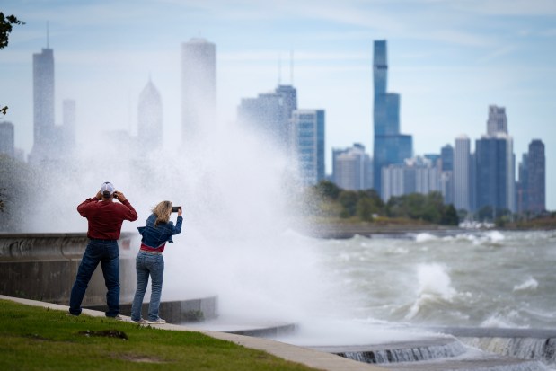 Monty and Jennifer Bruce of Colorado photograph the waves and gusty winds along the lakefront at 31st Street, the result of Hurricane Helene, according to the NWS on Friday, Sept. 27, 2024. (E. Jason Wambsgans/Chicago Tribune)