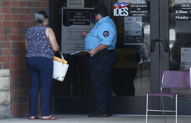 People review a list of COVID-19 screening questions posted outside an Illinois Department of Employment Security office in Harvey on Sept. 1, 2021. (Antonio Perez/Chicago Tribune)