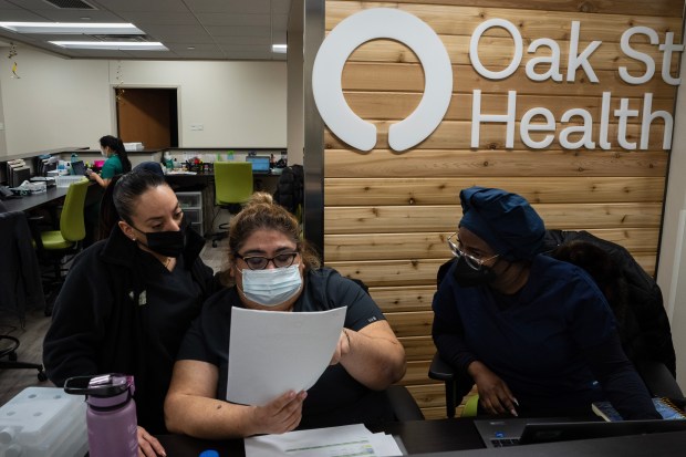 Employees discuss a patient's file at Oak Street Health in Bushwick, New York City, on Feb. 22, 2023. (James Estrin/The New York Times)