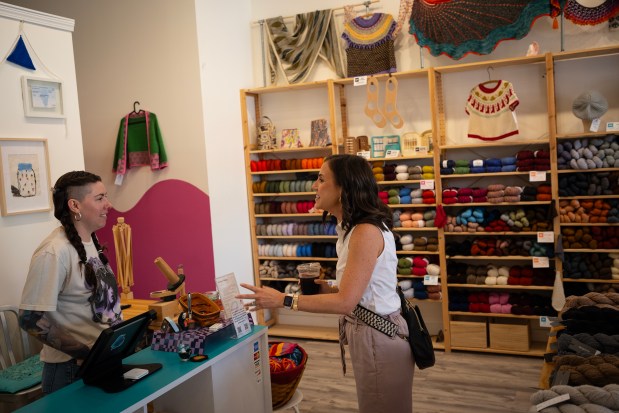 Liz Coffey stops to chat with Sarah Jamison, owner of Firefly Fiber Arts Studio in the Avondale neighborhood, as she scouts locations for her clients on Sep. 12, 2024. (E. Jason Wambsgans/Chicago Tribune)