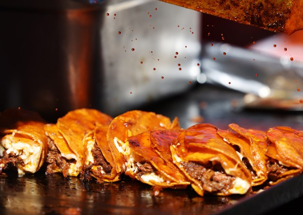 Juan Garcia splashes consomé on birria tacos from Tacotlán at the Taste of Chicago on Saturday, Sept. 7, 2024, in Chicago. (John J. Kim/Chicago Tribune)