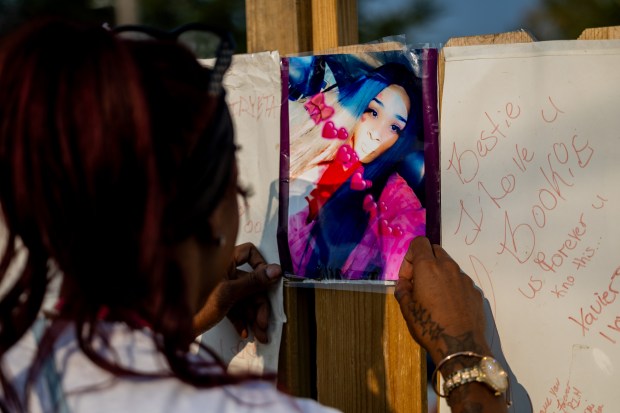 Aliyah Mason tapes a picture of Red to a memorial at a candlelit vigil on Sept. 11, 2024, honoring Red, a transgender woman who was shot and killed on Sept. 8, 2024, in the West Garfield Park neighborhood of Chicago. (Tess Crowley/Chicago Tribune)