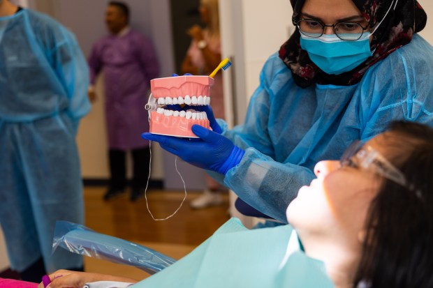 Fourth year UIC College of Dentistry student Rafia Awais shows patient Ivanna Chavez how to properly brush her teeth using a mold of teeth during a dental screening at UIC College of Dentistry's Inclusive Care Clinic in Chicago on Aug. 28, 2024. (Tess Crowley/Chicago Tribune)