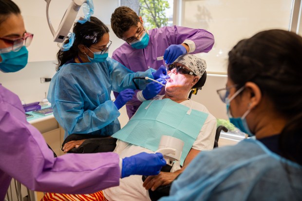 UIC College of Dentistry students assist faculty member Dr. Ivan Fry, center, as they treat patient Russell Plambeck at UIC's Inclusive Care Clinic in Chicago on Aug. 28, 2024. (Tess Crowley/Chicago Tribune)