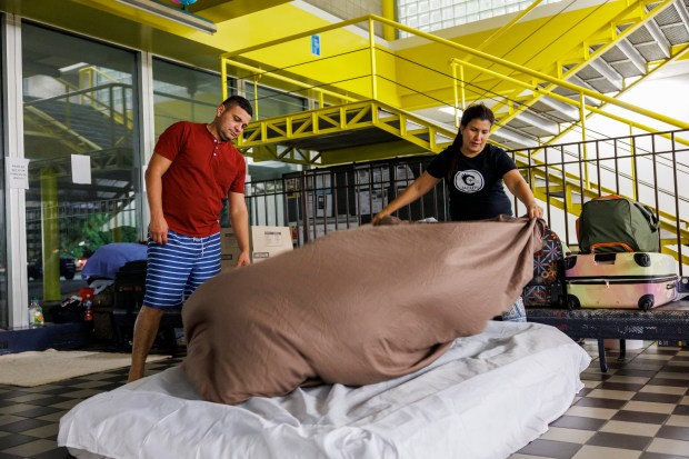 Carlos Ramirez and his wife Betzabeth Bracho make their bed before sleeping in the lobby of the District 5 police station on June 21, 2023, in Chicago.(Armando L. Sanchez/Chicago Tribune)