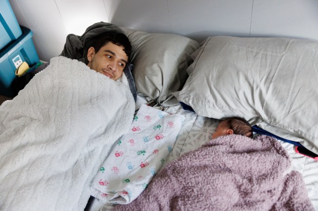 Marilieser Gil-Blanco, from Venezuela lays in bed with his one-month-old daughter, Ashley Gil, at their home in the Chatham neighborhood on Jan. 31, 2024, in Chicago. (Armando L. Sanchez/Chicago Tribune)