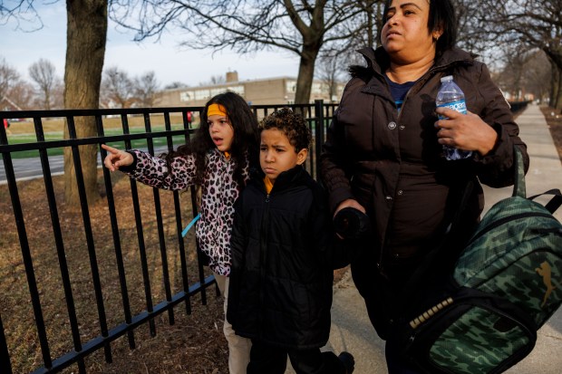 Angelica Beltran, 44, walks with her son Engerberth Morales, 8, center, while a family friend tries to comfort Morales outside Wentworth Elementary School in Englewood on Feb. 22, 2024 in Chicago. The family had attempted to take him to the school earlier in the week. (Armando L. Sanchez/Chicago Tribune)