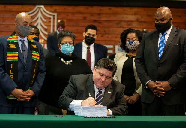 Gov. J.B. Pritzker is joined by lawmakers and community advocates as he signs HB 3653, a sweeping criminal justice and police reform bill, on Feb. 22, 2021, at Chicago State University. (Brian Cassella/Chicago Tribune)