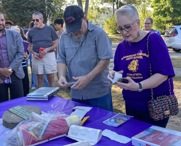 Gary Biggers and Jody Bishop Cruz peruse items removed from a time capsule buried at Waukegan High School when they were seniors there. (Steve Sadin/For the Lake County News-Sun)