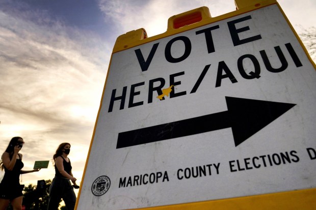 Voters deliver their ballot to a polling station in Tempe, Arizona on Nov. 3, 2021. A review of potential voter fraud cases in the 2020 general election in Arizona's second-largest county ended, Jan. 14, 2022, with an announcement by prosecutors that none of the 151 cases they reviewed merited criminal charges. The findings in Pima County provide yet another official rebuttal to former President Donald Trump's claims that voter fraud led to his loss in Arizona and other battleground states.