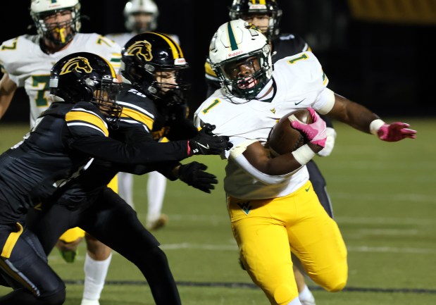 Waubonsie Valley's Chrisjan Simmons, right, runs the ball through a crowd of Metea Valley players during a game in Aurora on Friday, Oct. 25, 2024. (James C. Svehla / for the Beacon-News)