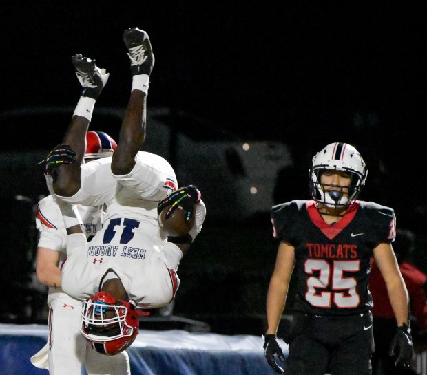 West Aurora's Kewon Marshall (11) does a back flip to celebrate his 2nd, second quarter touchdown as East Aurora's Julian Olivas (25) looks on in Aurora on Friday, Oct. 18, 2024. (Mark Black / for the Beacon-News)