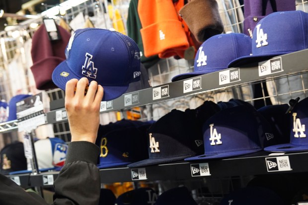 A customer picks up a cap, one of the character goods of Shohei Ohtani of the Los Angeles Dodgers, at a sporting goods store, "SELECTION," in Shinjuku district Wednesday, Dec. 13, 2023, in Tokyo. (AP Photo/Eugene Hoshiko)