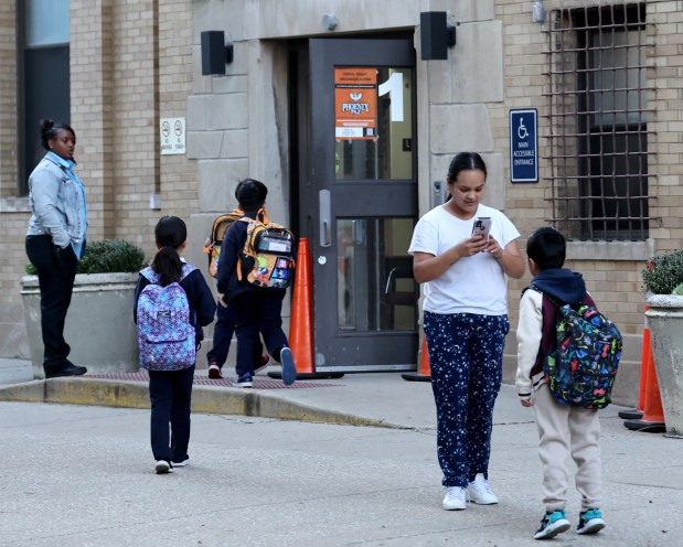 Karen Romero, right, arrives with her two children at Paz Elementary School, 2651 W. 23rd Street, in Chicago, Oct. 10, 2024. Paz is part of the Acero Charter School Network in Chicago, which has announced planned school closures for the 2025 school year, including Paz Elementary School. (Antonio Perez/Chicago Tribune)