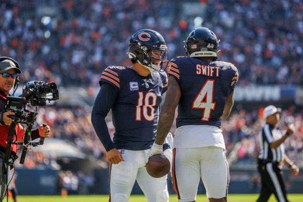 Bears running back D'Andre Swift (4) celebrates with quarterback Caleb Williams after scoring a touchdown during the second quarter against the Panthers on Oct. 6, 2024, at Soldier Field. (Armando L. Sanchez/Chicago Tribune)