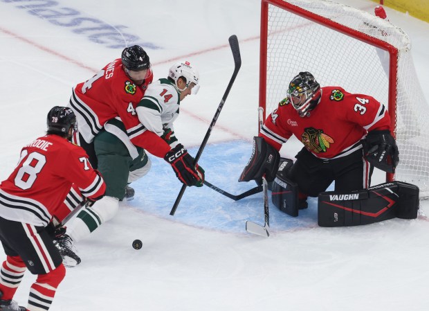 Wild center Joel Eriksson Ek (14) is pushed by Blackhawks defenseman Seth Jones (4) as goaltender Petr Mrazek (34) defends the goal in the first period of a preseason game at the United Center on Oct. 4, 2024, in Chicago. (John J. Kim/Chicago Tribune)