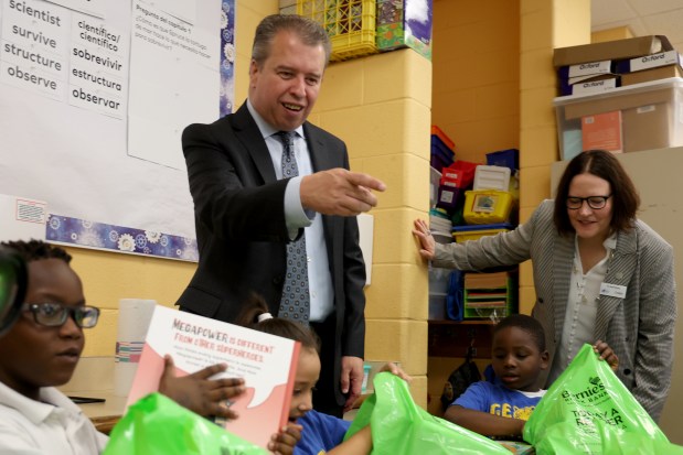 Chicago Public Schools CEO Pedro Martinez helps distribute donated books to 1st graders at Armstrong International Studies school on Sept. 30, 2024. (Antonio Perez/Chicago Tribune)