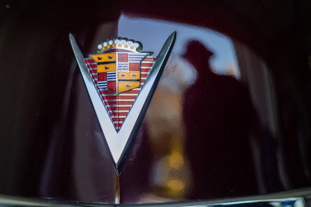 Vice president of the Pura Familia Car Club Art Martin's reflection can be seen next to the Cadillac V on his 1947 Cadillac convertible, which he will ride in next year's Chicago Lowrider Festival at Navy Pier, at his home in Shorewood on Oct. 8, 2024. (Tess Crowley/Chicago Tribune)