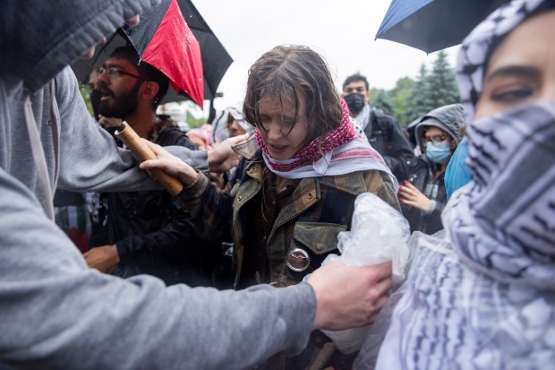 A pro-Palestine protester reacts after being pepper sprayed by UCPD officers as the protesters attempt to break through an erected barrier at E 59th and S University Ave. during a rally after University of Chicago students walked out of the university's convocation ceremony in support of Palestine on Saturday, June 1, 2024, in Chicago. (Vincent Alban/Chicago Tribune)