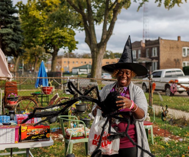 Hope Griffin resets a giant spider after it was blown over in the wind while waiting for trick-or-treaters in the Englewood neighborhood Oct. 31, 2024. (Armando L. Sanchez/Chicago Tribune)