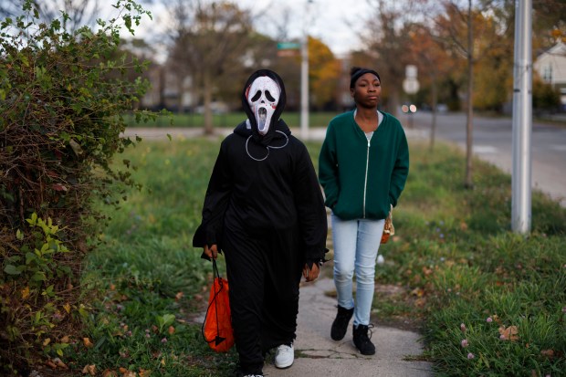 Ladale Coleman, 11, left, and Serenity Morrison, 13, go trick-or-treating in the Englewood neighborhood, Oct. 31, 2024. (Armando L. Sanchez/Chicago Tribune)