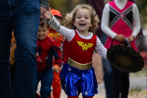 Jo Bugg, 3, trick or treats dressed as Wonder Woman on Halloween in the Roscoe Village neighborhood of Chicago on Oct. 31, 2024. (Tess Crowley/Chicago Tribune)