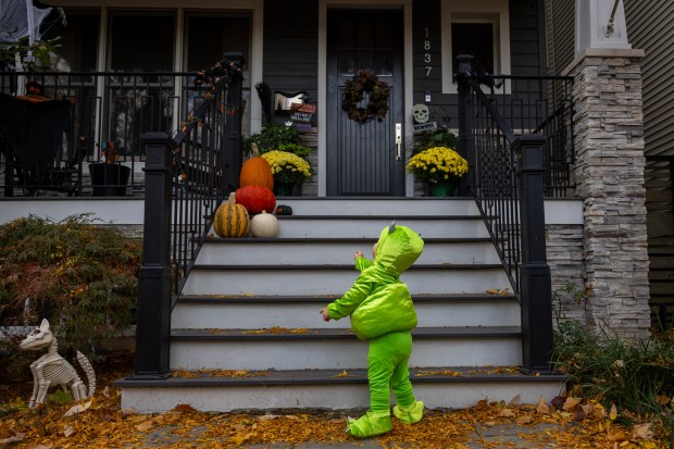 Oliver Fansler, 1, trick or treats dressed as Mike Wazowski on Halloween in the Roscoe Village neighborhood of Chicago on Oct. 31, 2024. (Tess Crowley/Chicago Tribune)