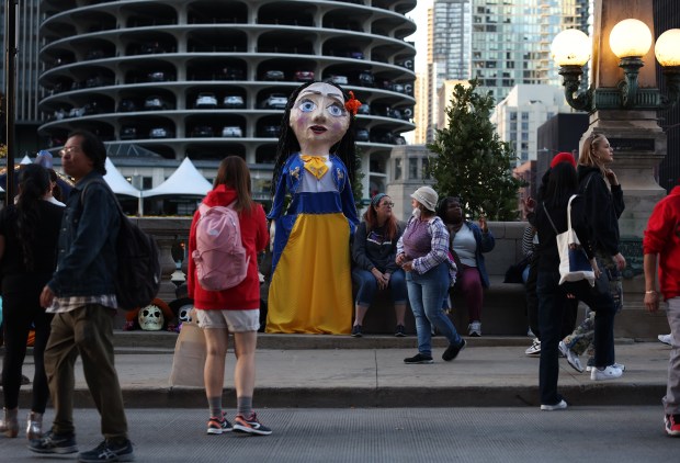 A person dressed as a walking puppet stands with parade watchers before marching in the Arts in the Dark Halloween Parade. (John J. Kim/Chicago Tribune)